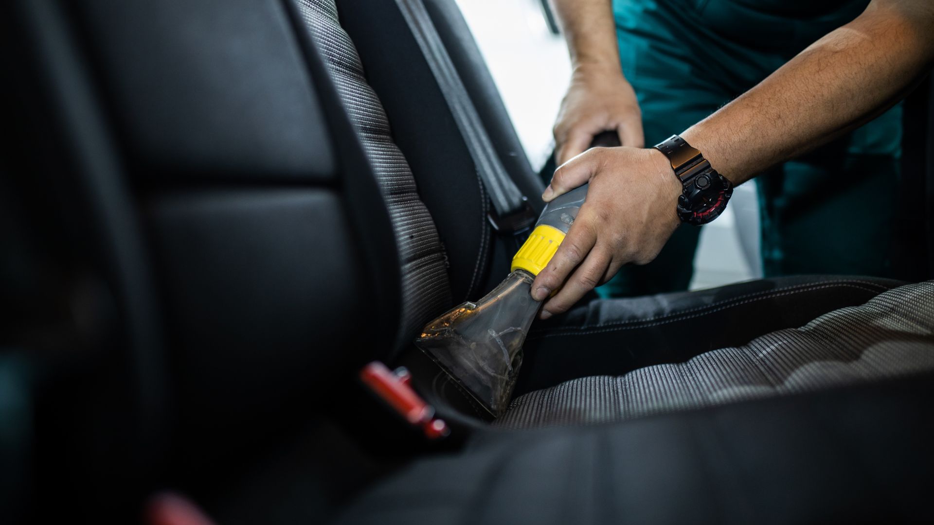 A man cleaning a car seat with a sponge