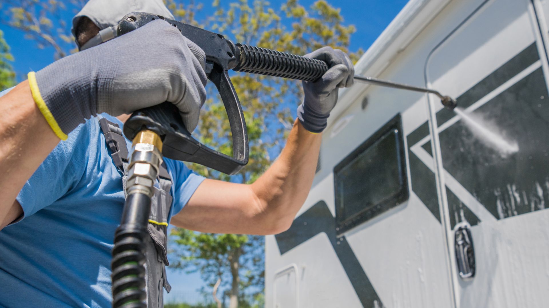 A man spray painting a trailer with a spray gun