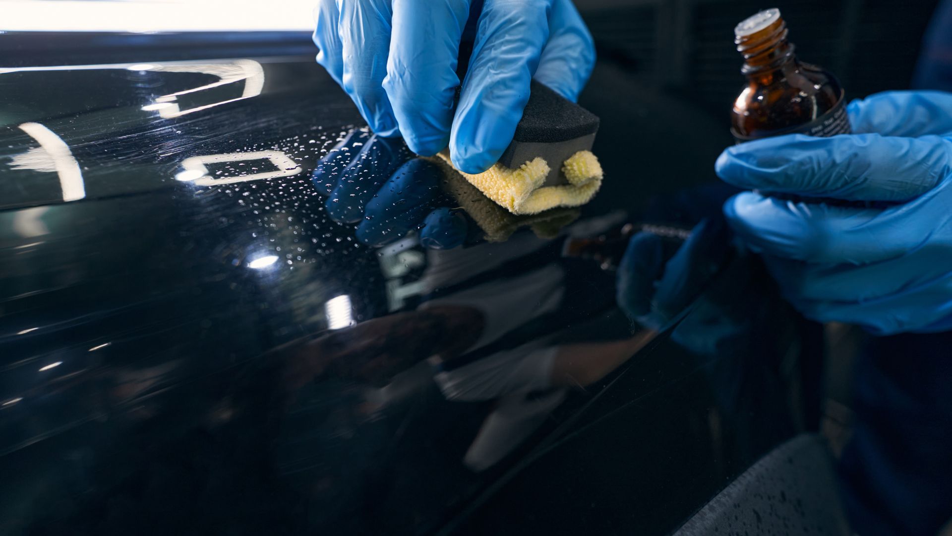 A person in blue gloves is cleaning a car